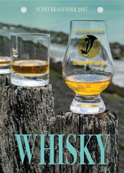 Foto van verschillende glazen whiskey op houten palen aan de Ierse kust.
